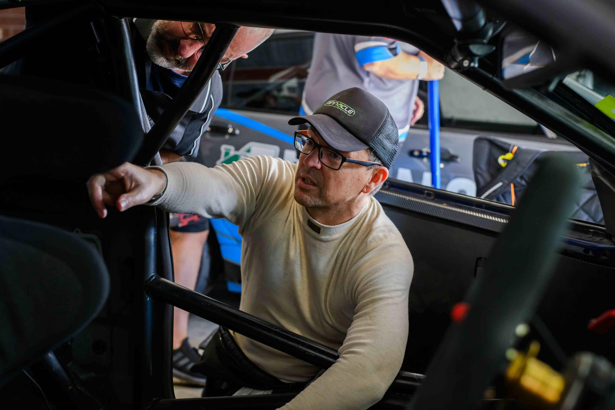 Driver and crew discussing setup beside the race car before going out